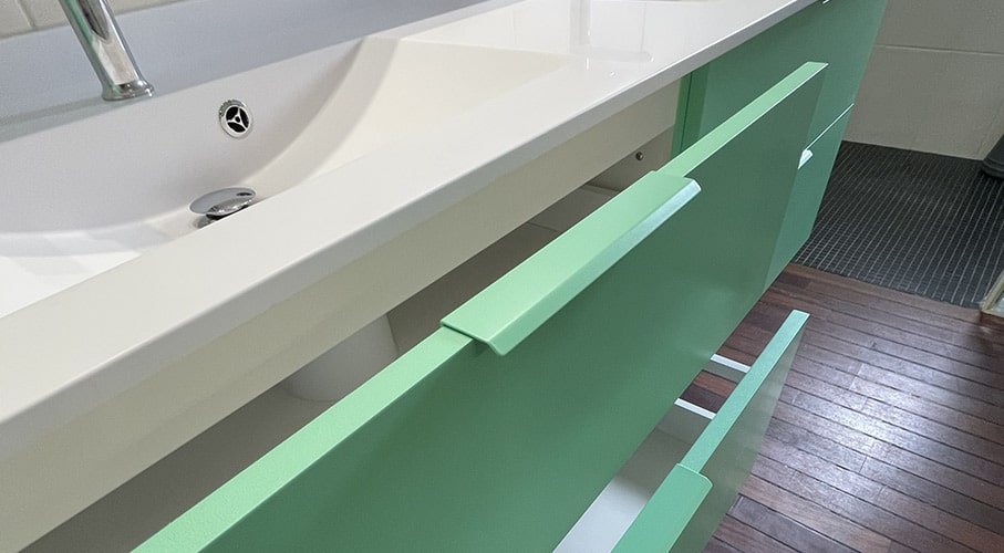 poignée de meuble fixée sur le chant de la porte de la meme couleur verte que la façade